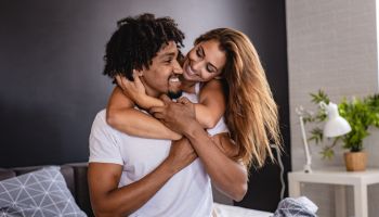 Young couple at home in bed smiling